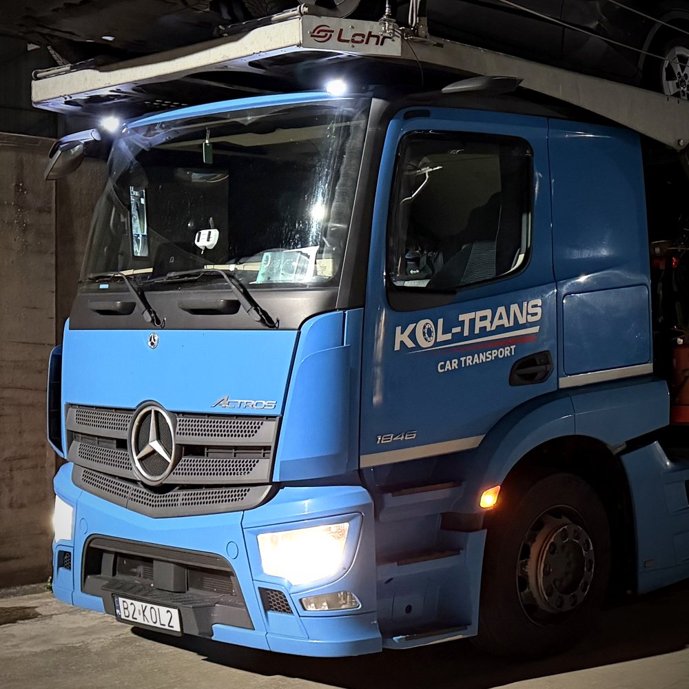 Kabina niebieskiego autotransportera Mercedes-Benz Actros Kol-Trans z logo Kol-Trans Car Transport, nocą na placu w Belgii